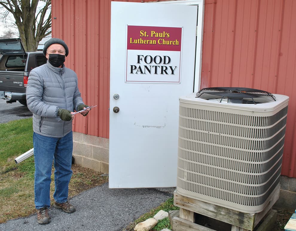 A volunteer stands near the door of the St. Paul Lutheran Church Food Pantry during a Wednesday food distribution in Mill Hall, Pennsylvania