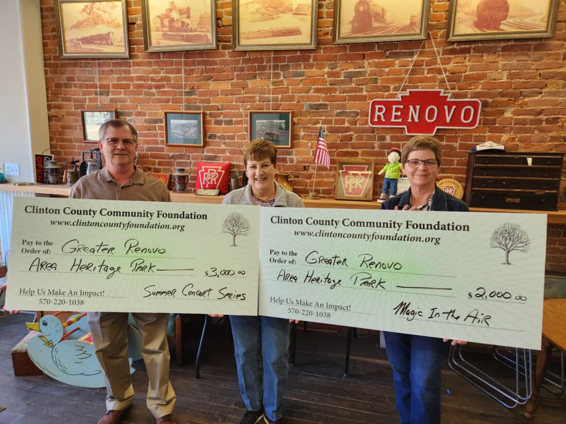 Three people stand among historical exhibits inside the Greater Renovo Area Heritage Park museum on Erie Avenue in Renovo, PA, during a grant presentation.
