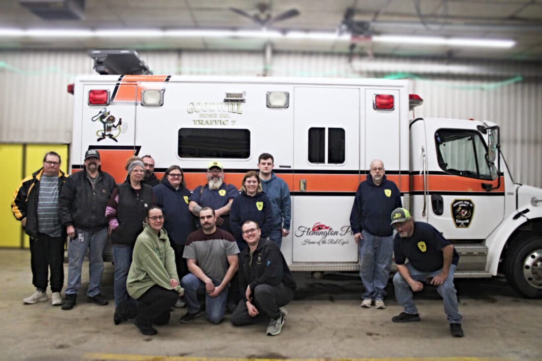 Goodwill Hose Company members and community donors pose in front of the Traffic 7 unit, lettered Goodwill Hose Co. Traffic 7 and Flemington PA, inside the Flemington fire station.