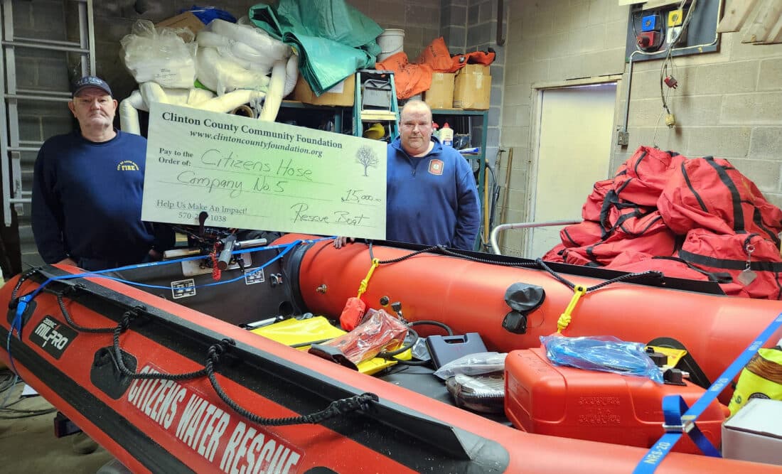 Two Lock Haven Citizens Hose Company firefighters standing beside a new inflatable rescue boat at Station 6