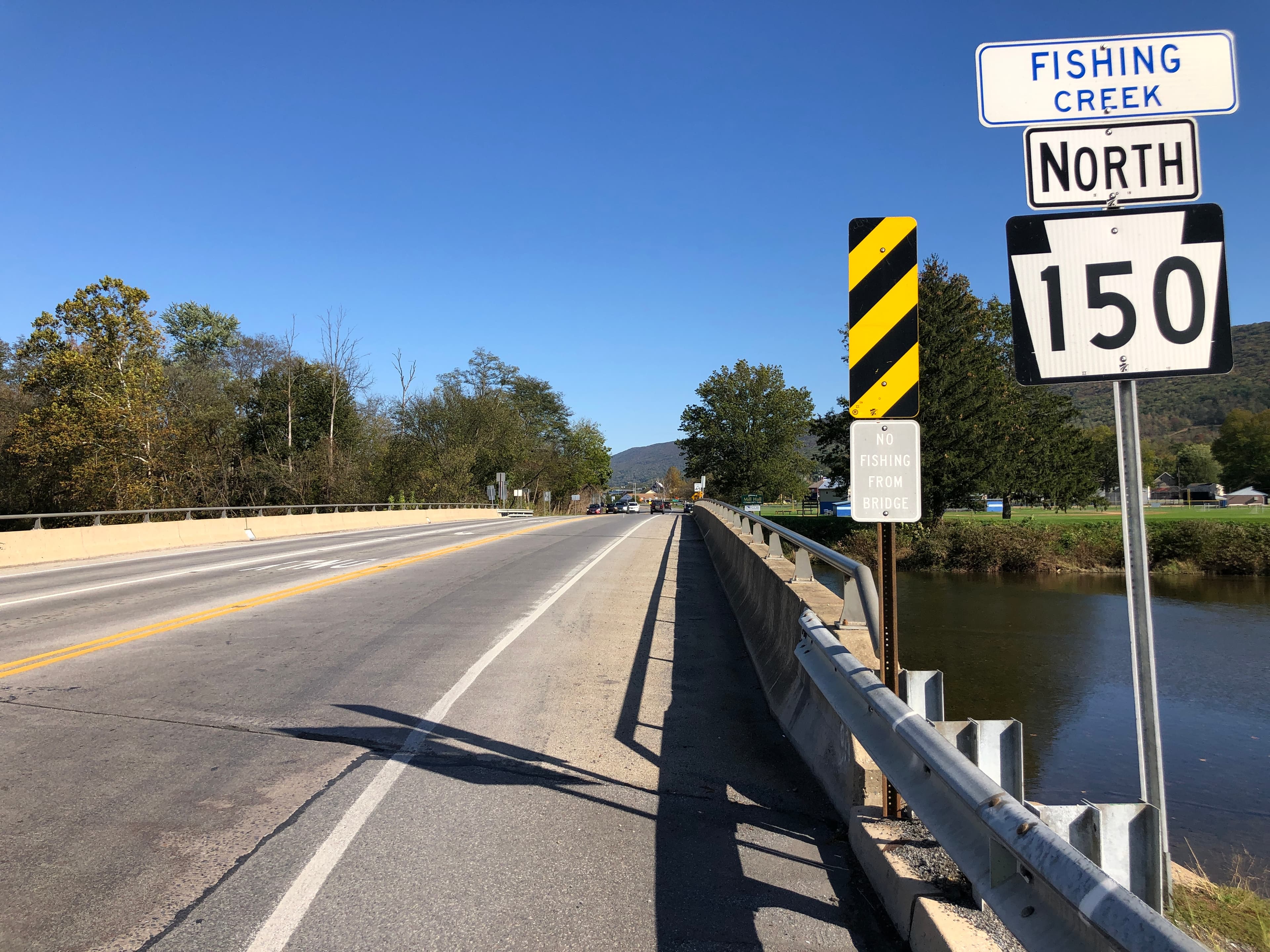 Fishing Creek flowing under a rural road at the Mill Hall border in Clinton County, Pennsylvania, with trees and countryside