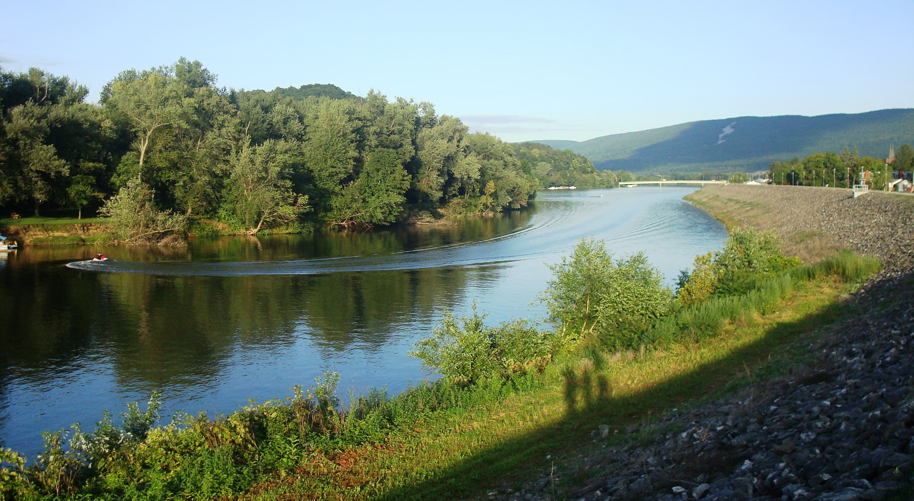 The West Branch Susquehanna River flowing downstream from Lock Haven under a partly cloudy sky, the stretch that passes McElhattan